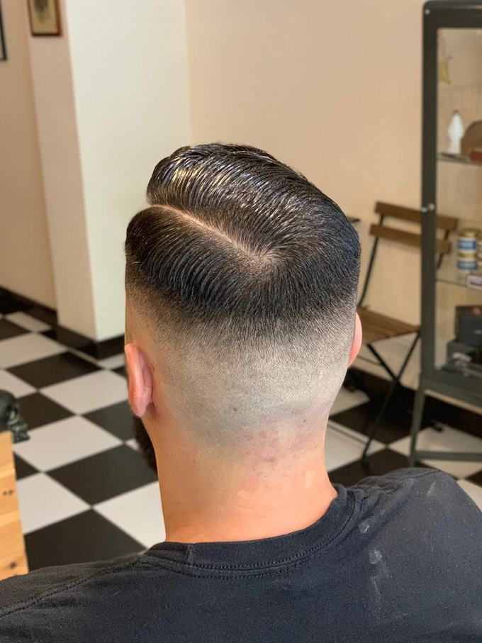 Corte com risco lateral e degradê, barba aparada — visto de trás