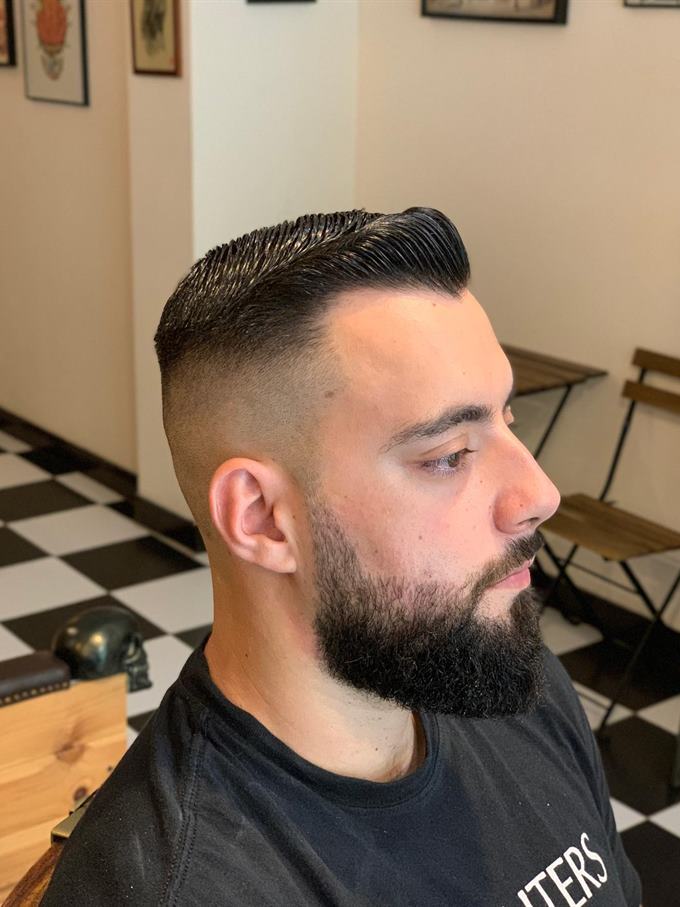 Corte com risco lateral e degradê, barba aparada — do outro lado