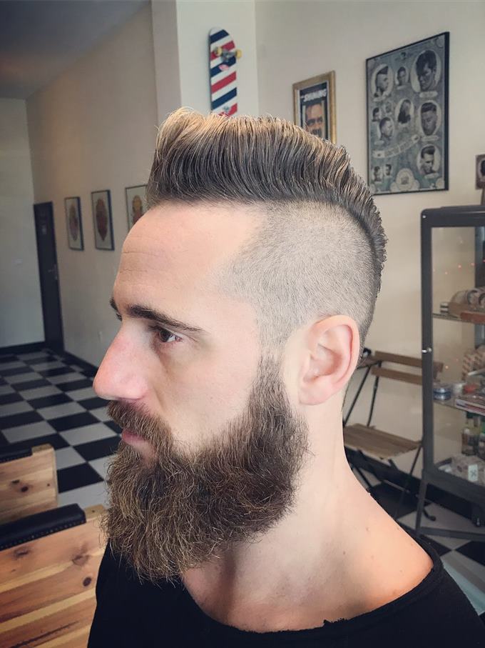 Undercut desligado com topo volumoso e barba cheia — de perfil